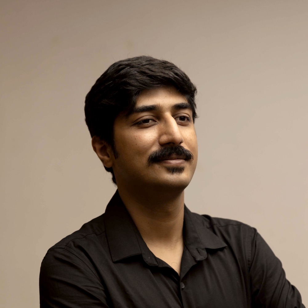 Shivam Bhatnagar, looking off-camera against a warm beige wall
